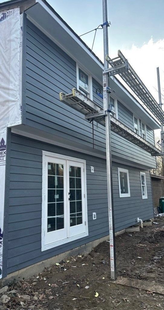 A large house with a brown roof, light brown siding, and white trim