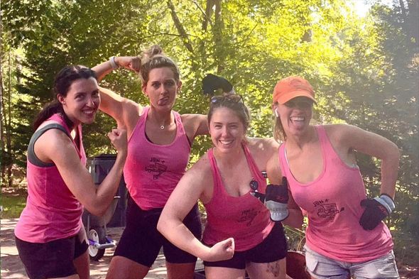 A group of women in pink tank tops are posing for a picture.