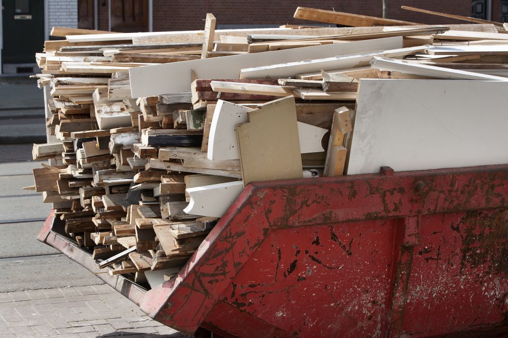 Red Dumpster Overflowing With Discarded Wood and Debris on a Street — Red e Bins in Bonny Hills, NSW