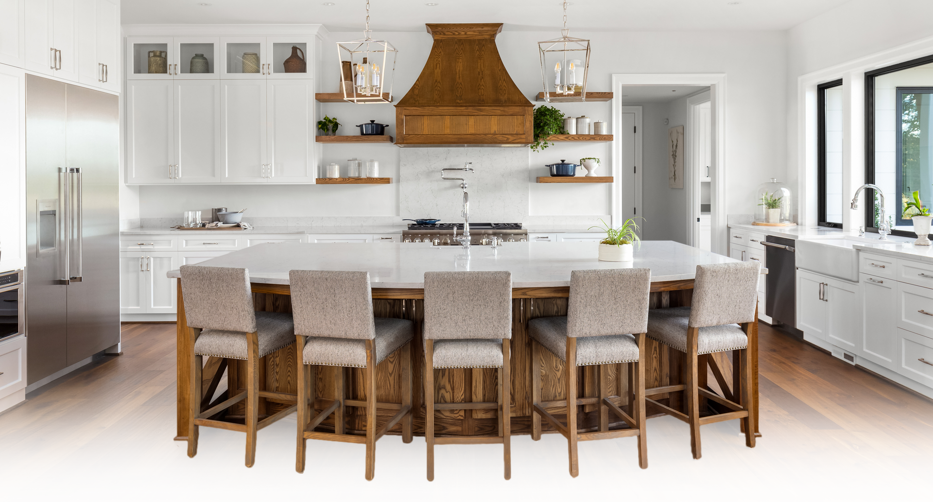 White kitchen with wooden island, range hood, and bar stools.