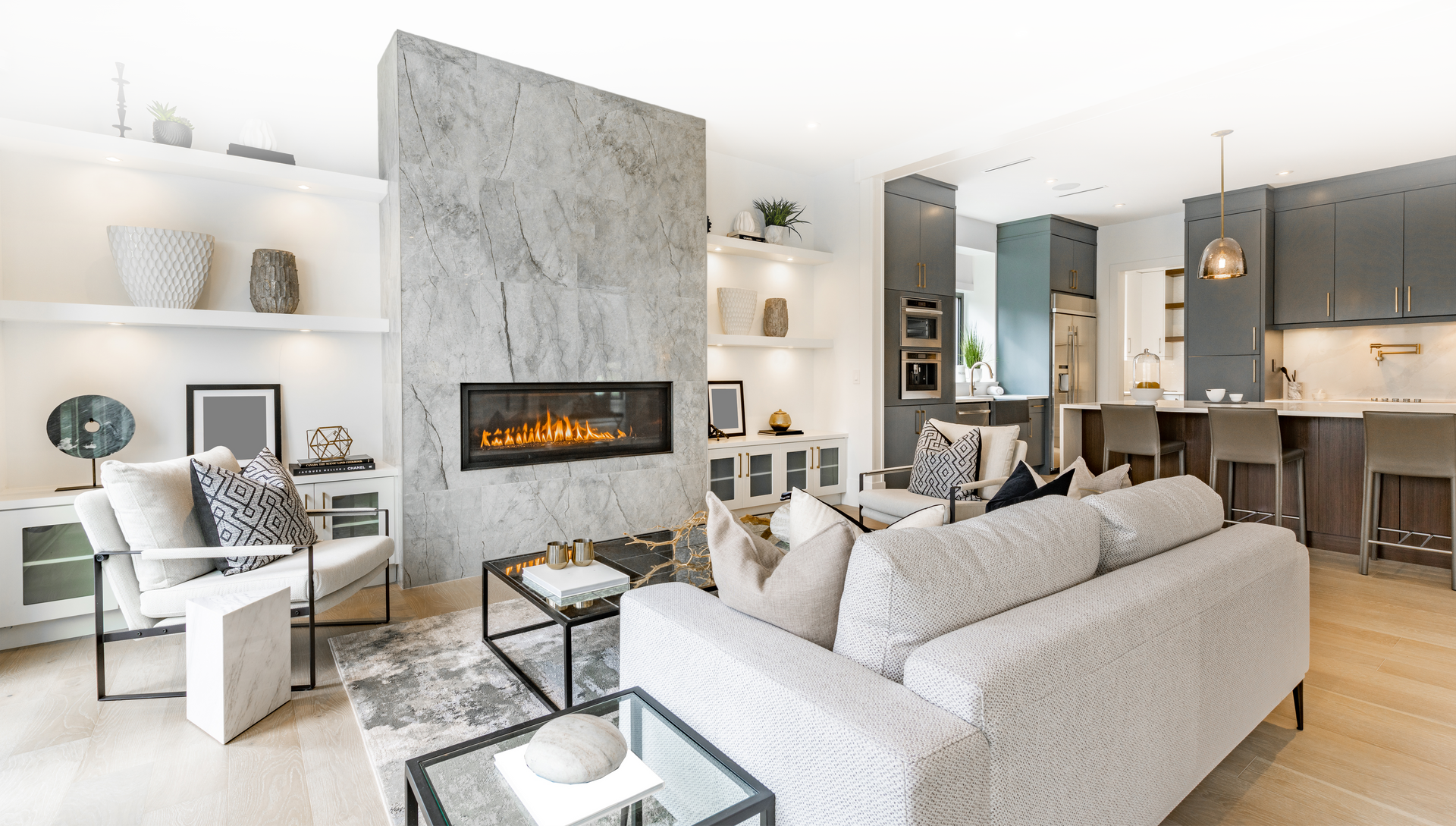 Modern living room with fireplace, open kitchen, and light-colored furniture.