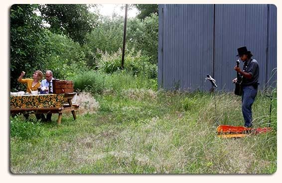 man playing guitar for couple during picnic