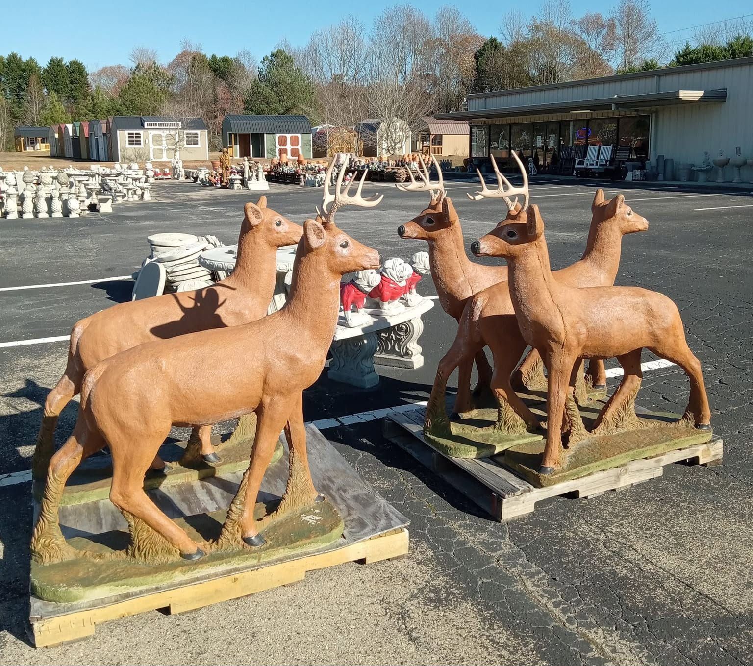 A group of deer statues are sitting on wooden pallets in a parking lot