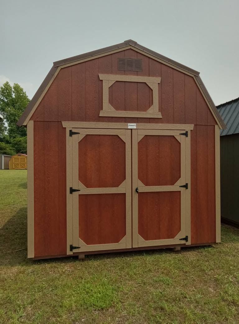 A red barn is sitting in the middle of a grassy field.