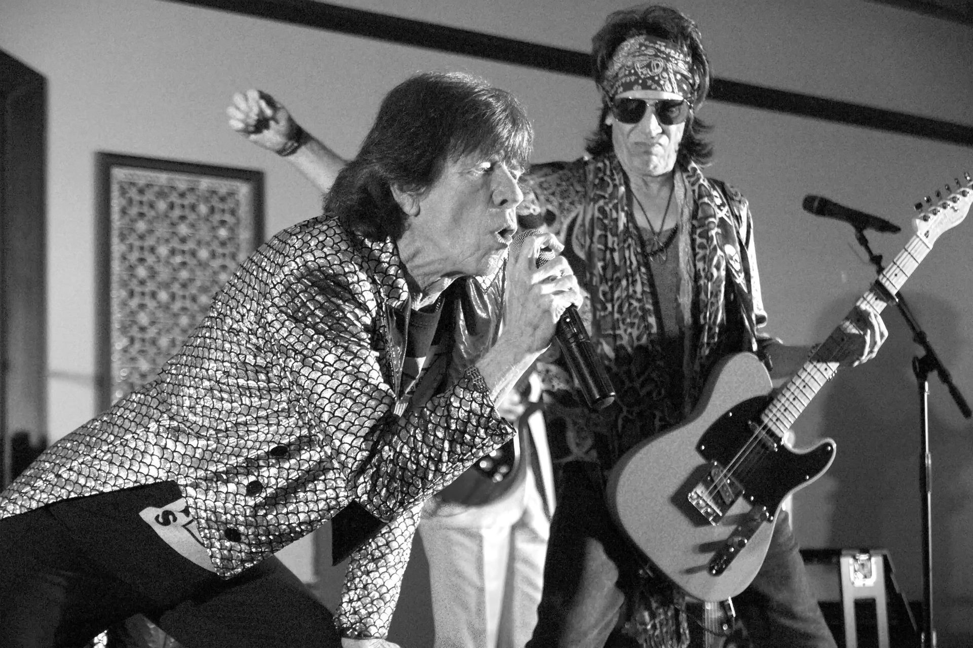 Black-and-white photo of a singer at a microphone with a guitarist on stage.