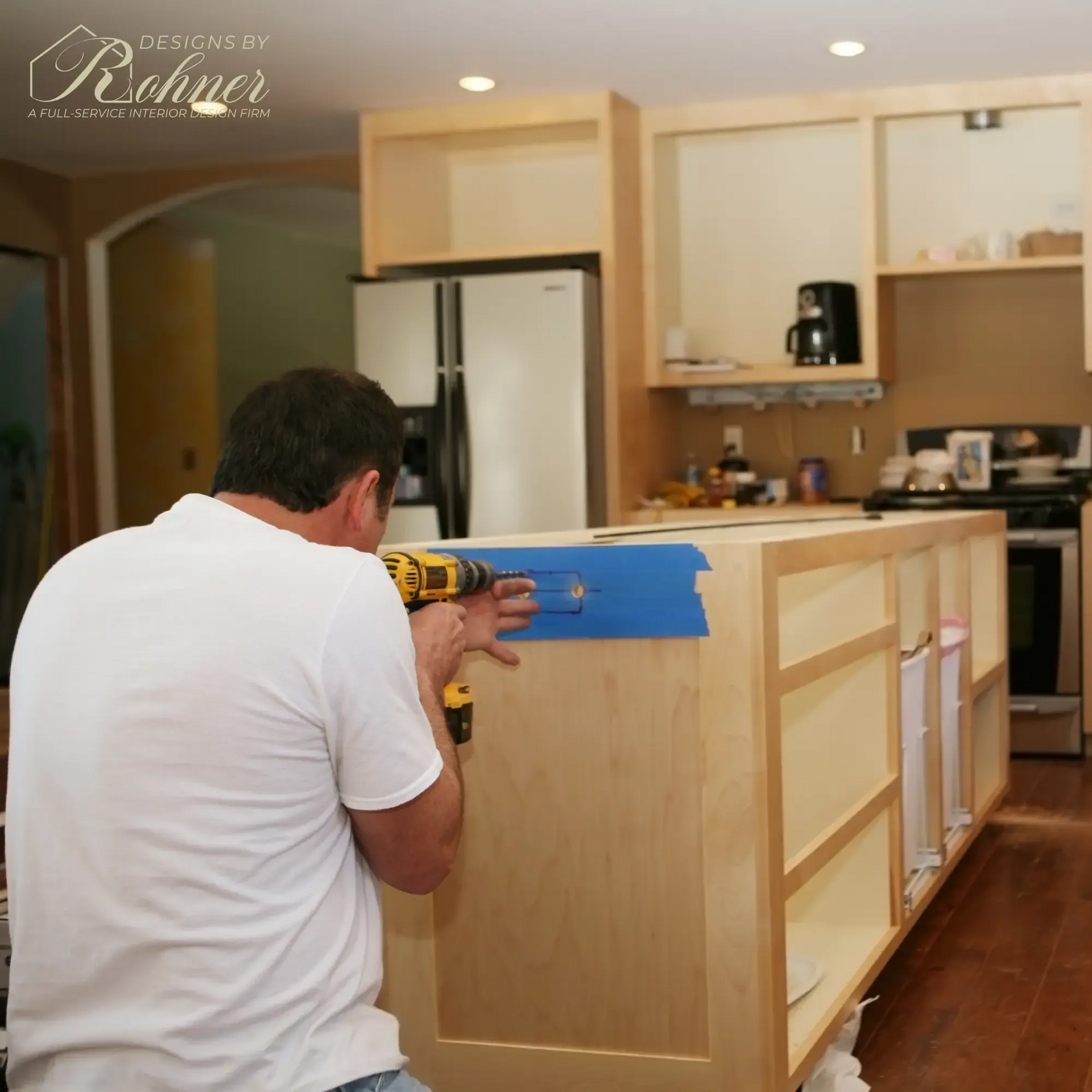 Man drills cabinet in kitchen during renovation.