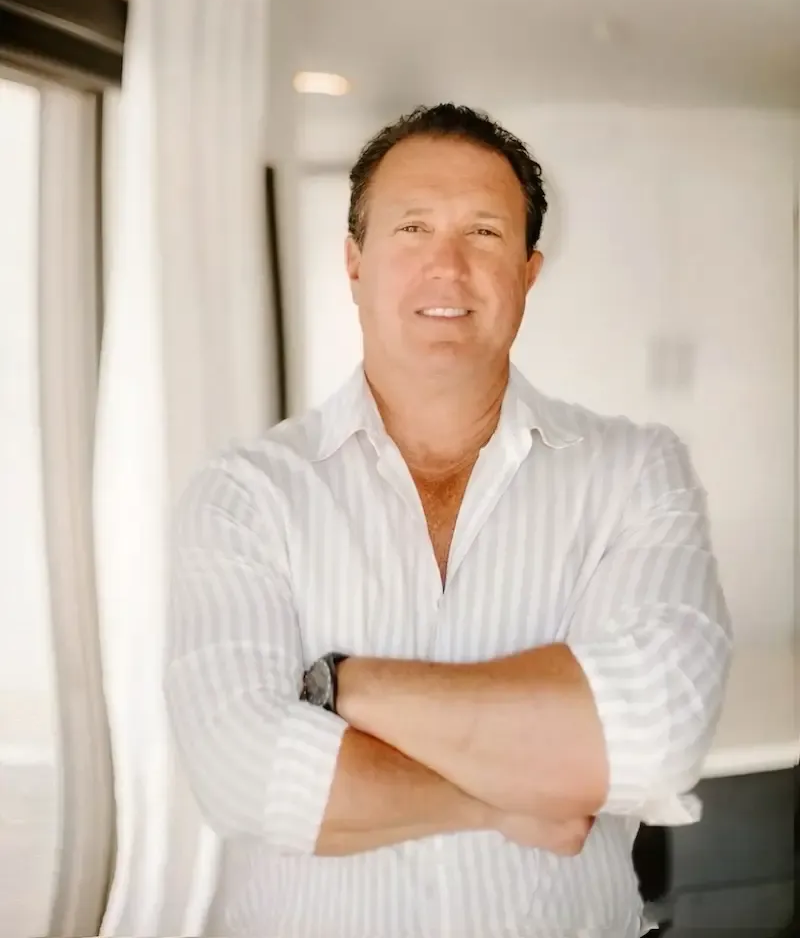 Man in white shirt with arms crossed, smiling.
