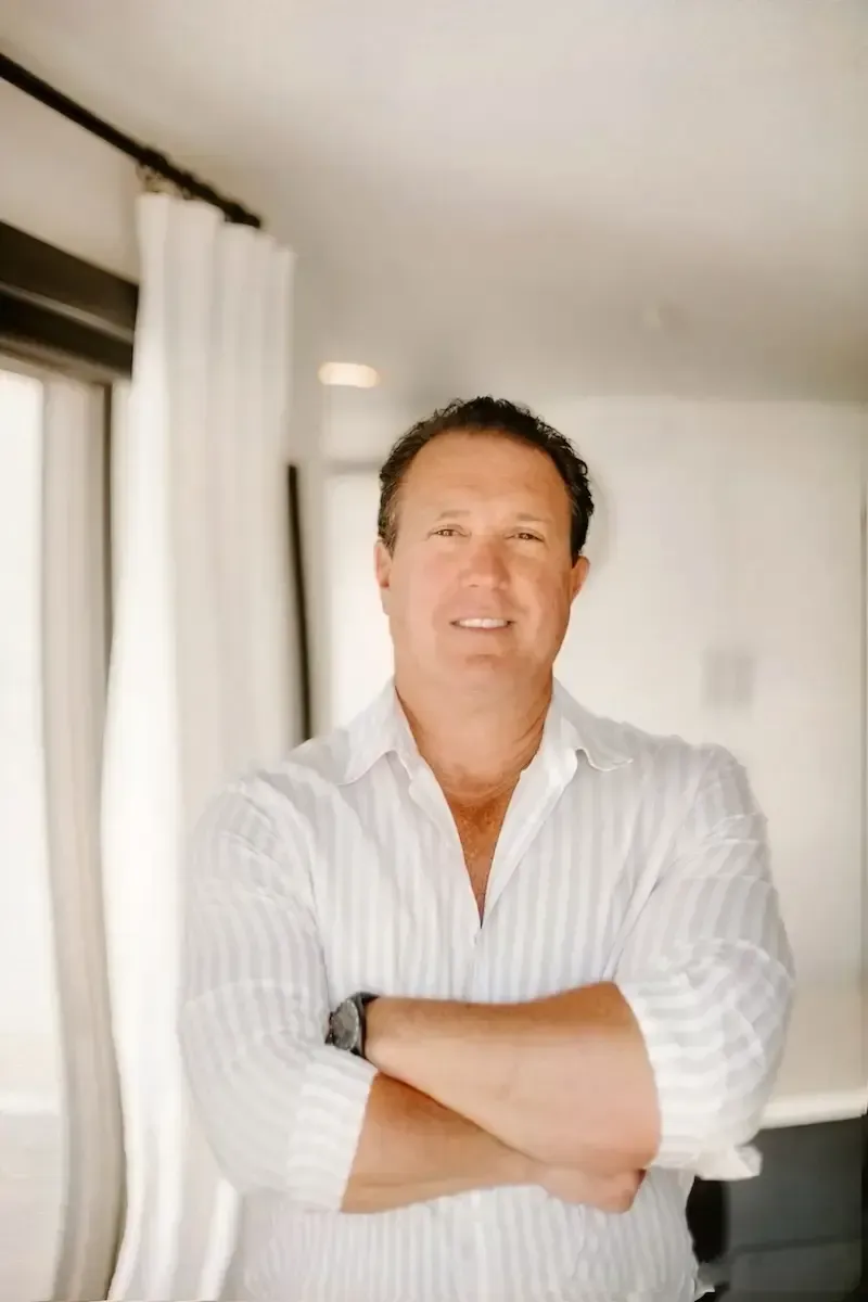 Man in white shirt with arms crossed, smiling.