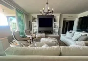 Living room with white sofas, chairs, fireplace, and chandelier.