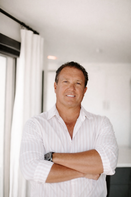 Man in white shirt with arms crossed, smiling.