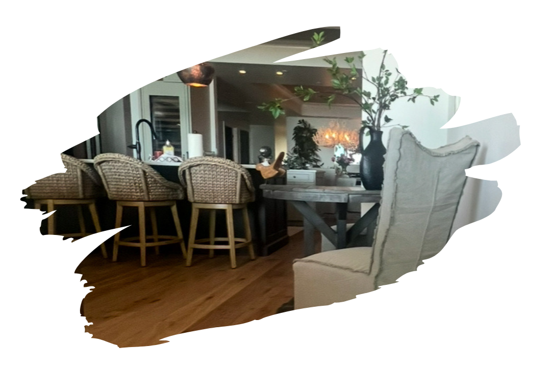 Kitchen with wood floors, island with woven bar stools, and a round table with a linen chair.