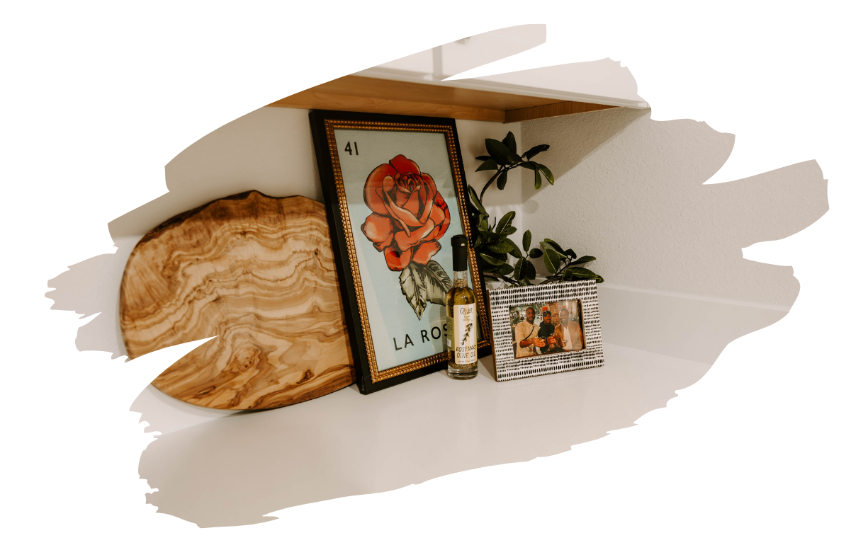 Shelf with framed rose art, a wood slice, small plants, and a photo frame.