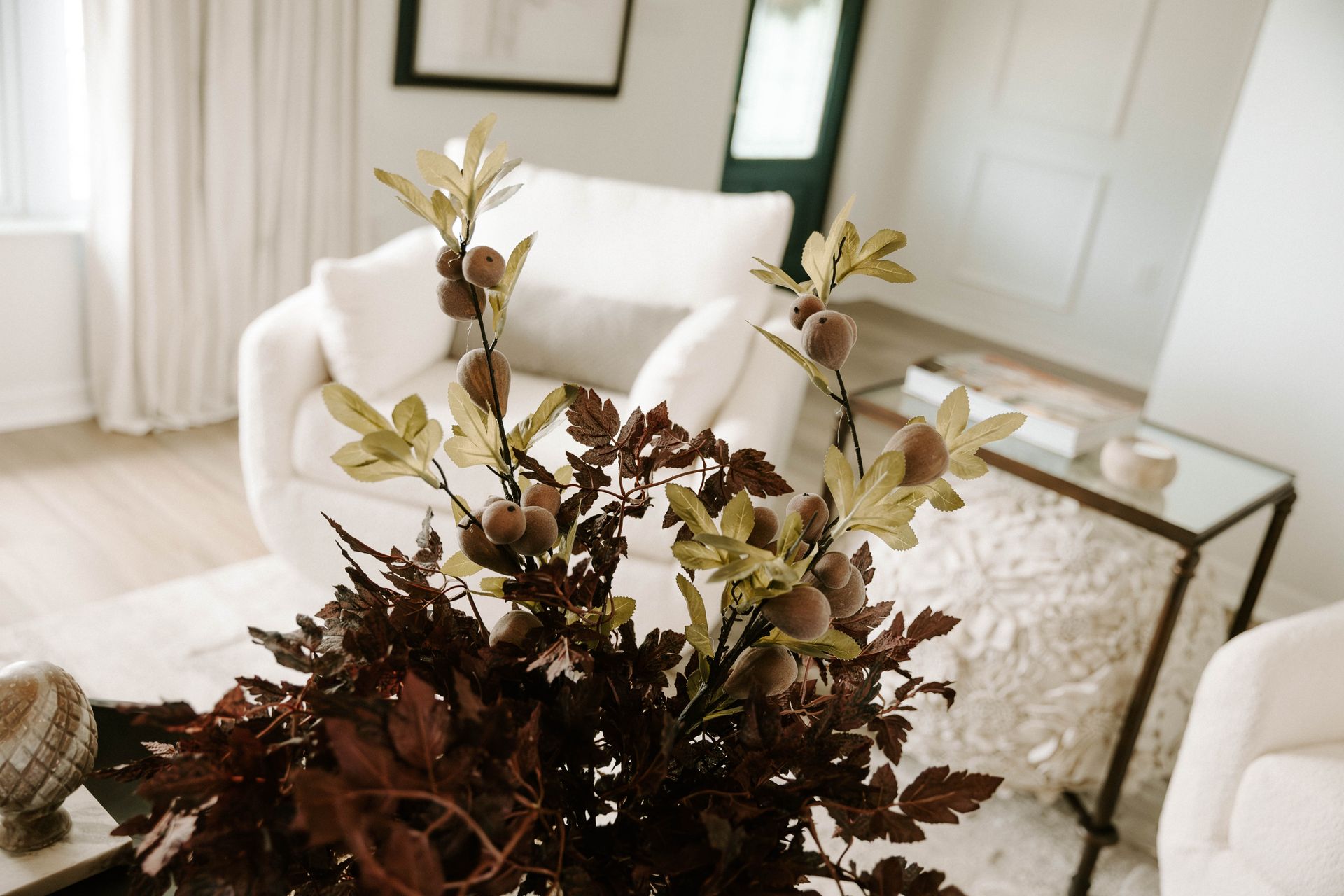 Dark-walled bathroom with light wood vanity, round gold mirrors, and a potted plant.