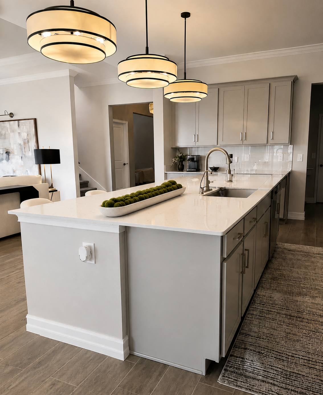 Modern kitchen with white island, pendant lights, sink, and gray cabinets