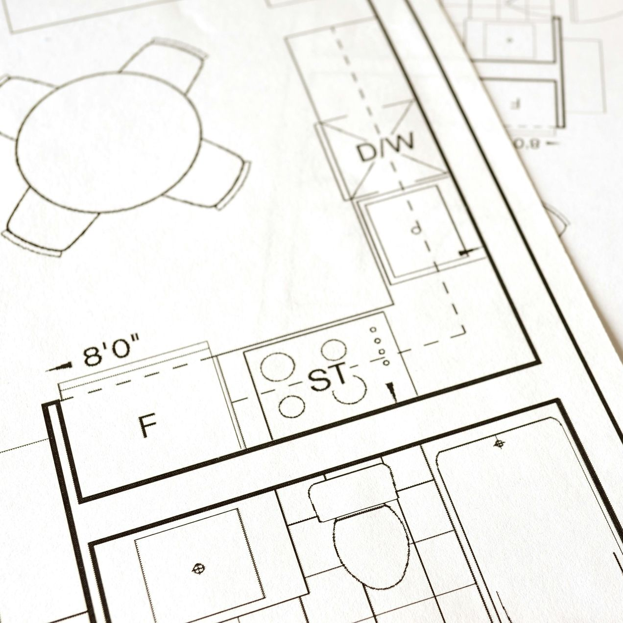 Architectural blueprint detail: kitchen and bathroom layout, including stove, dishwasher, and a round table.