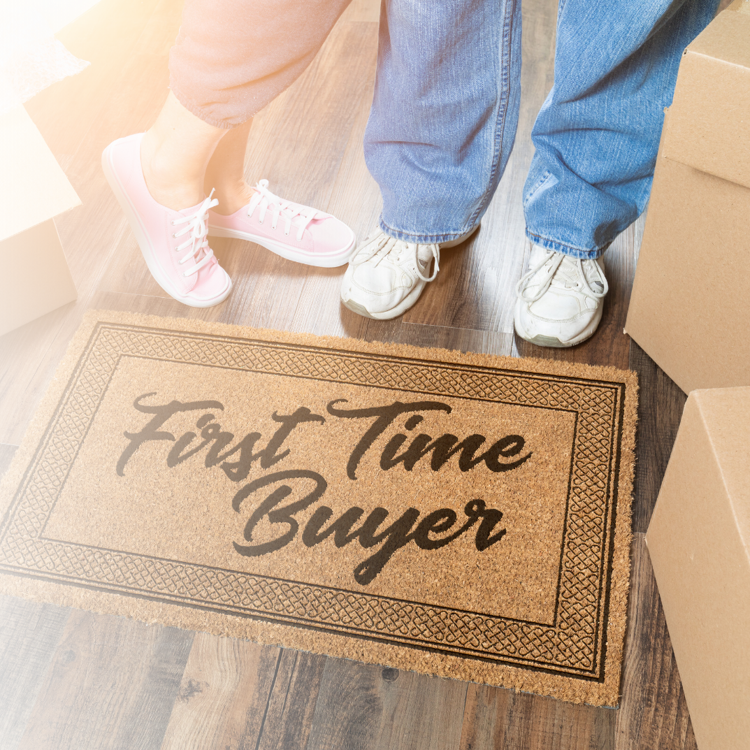A couple is standing next to a door mat that says `` first time buyer ''.