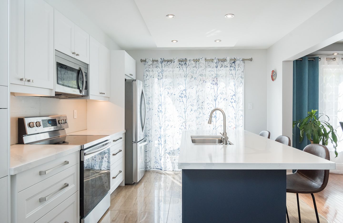 A kitchen with white cabinets , stainless steel appliances , and a large island.