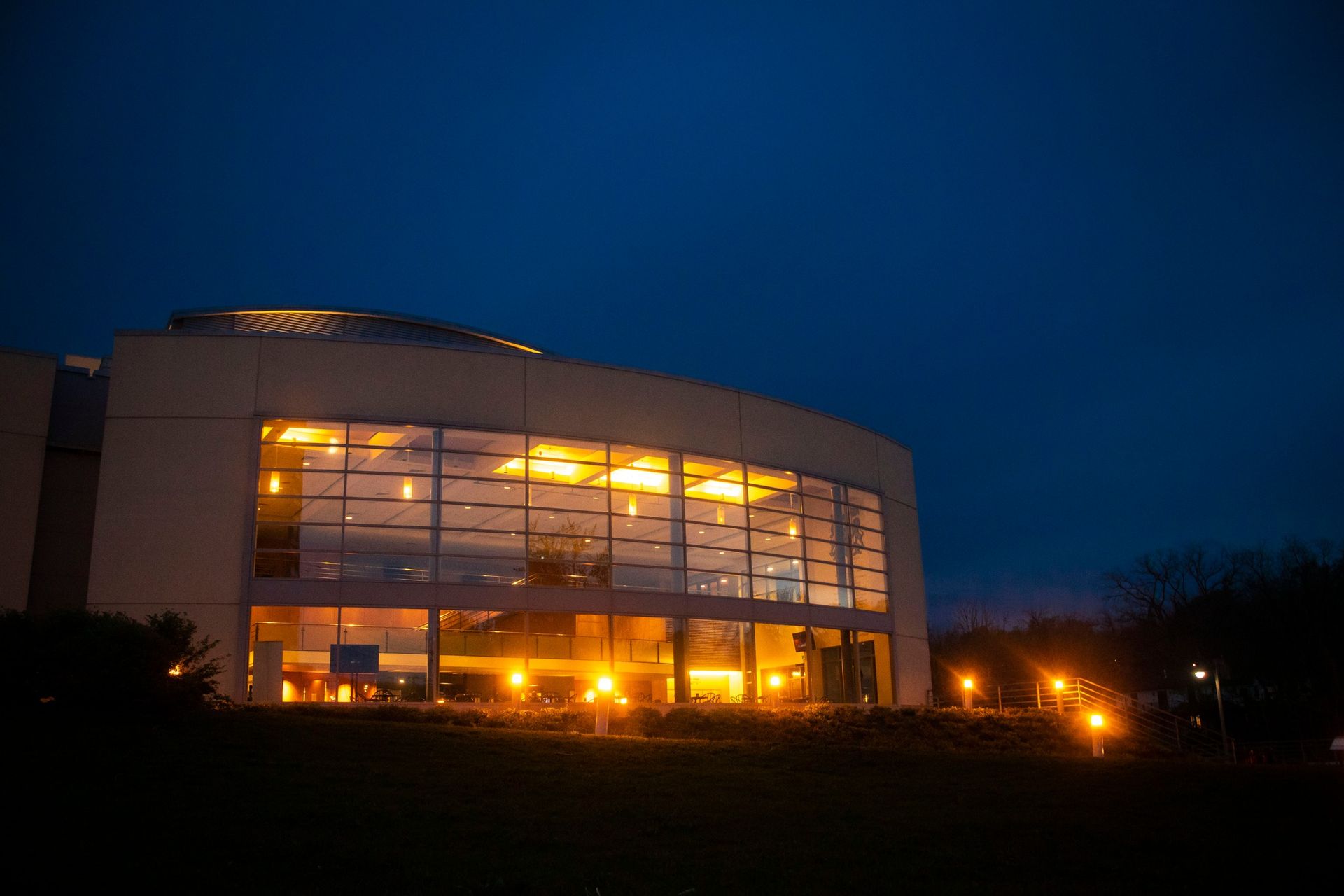 Modern building with large windows illuminated at dusk.