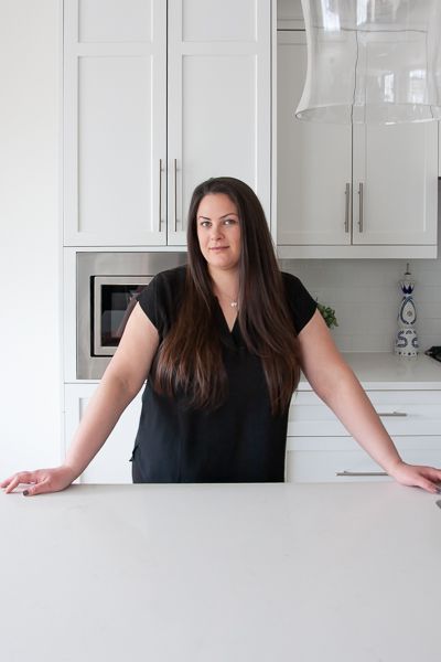 Woman in black top, arms outstretched, in a white kitchen.