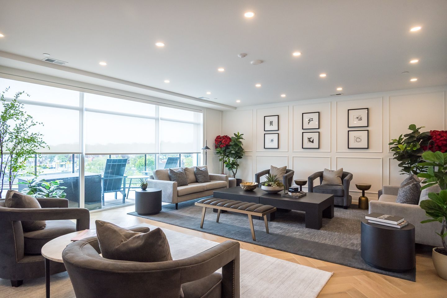 Modern living room with gray furniture, large windows, plants, and decorative wall art.
