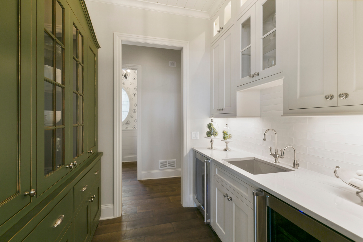 A kitchen with green cabinets , white cabinets , a sink and a refrigerator.