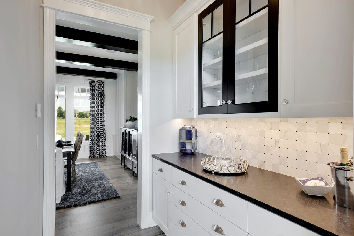 A kitchen with white cabinets and black counter tops.