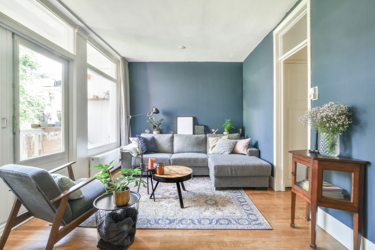 A living room with blue walls , a couch , chairs , and a table.