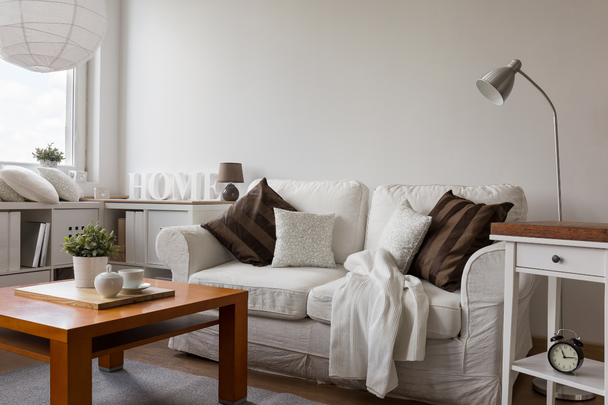 A living room with a couch , coffee table , lamp and clock.