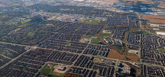 Aerial view of a suburban neighborhood with houses, roads, and some green spaces.