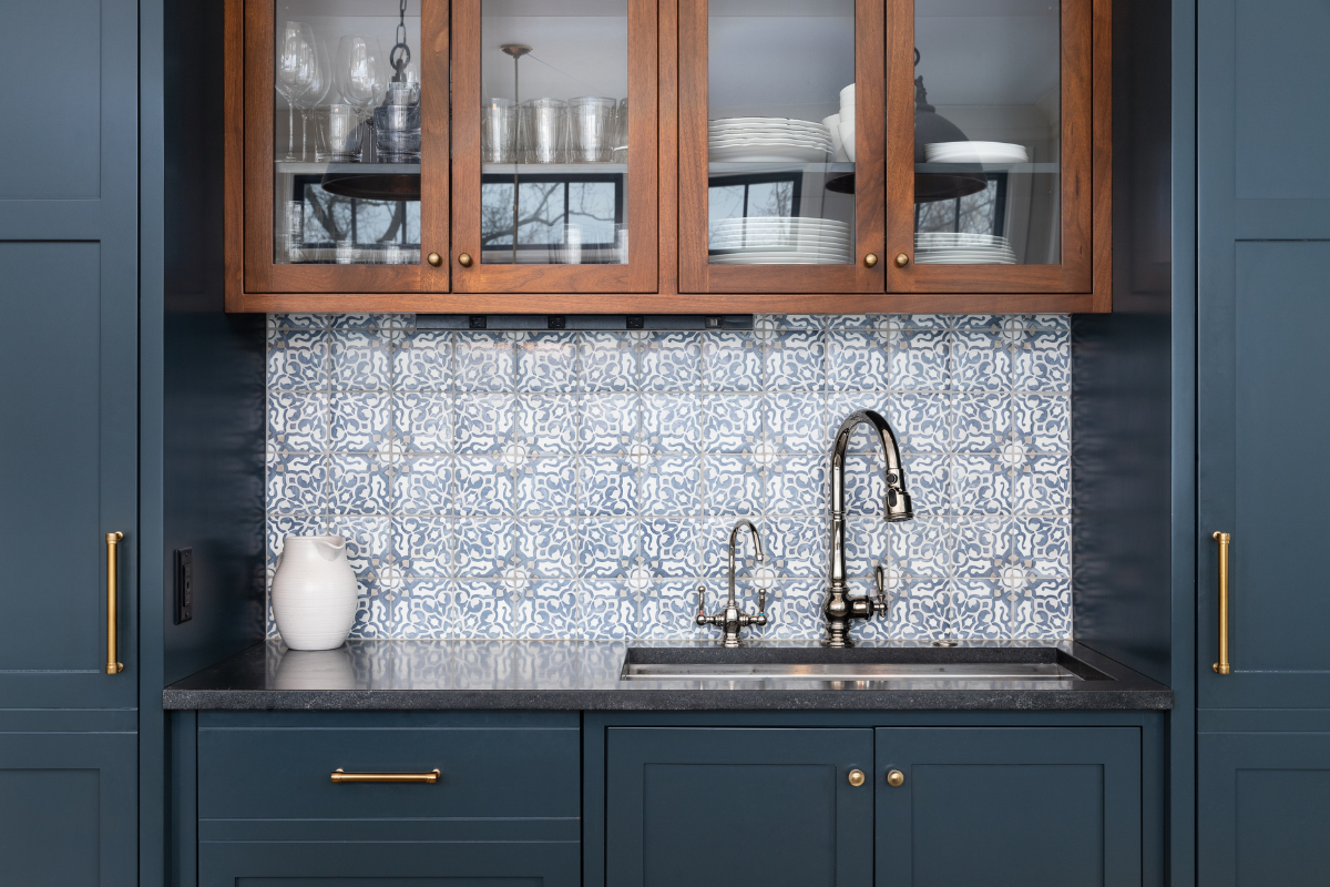 A kitchen with blue cabinets and a sink with a glass door.