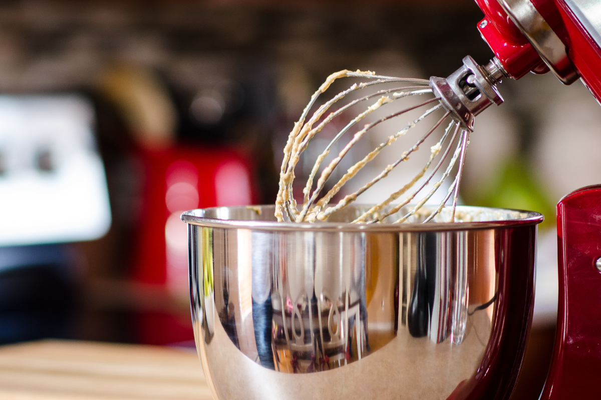 A red kitchenaid mixer with a whisk in a bowl