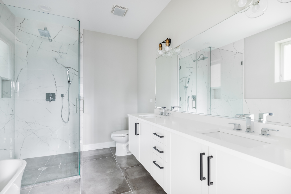 A bathroom with two sinks , a toilet , and a walk in shower.