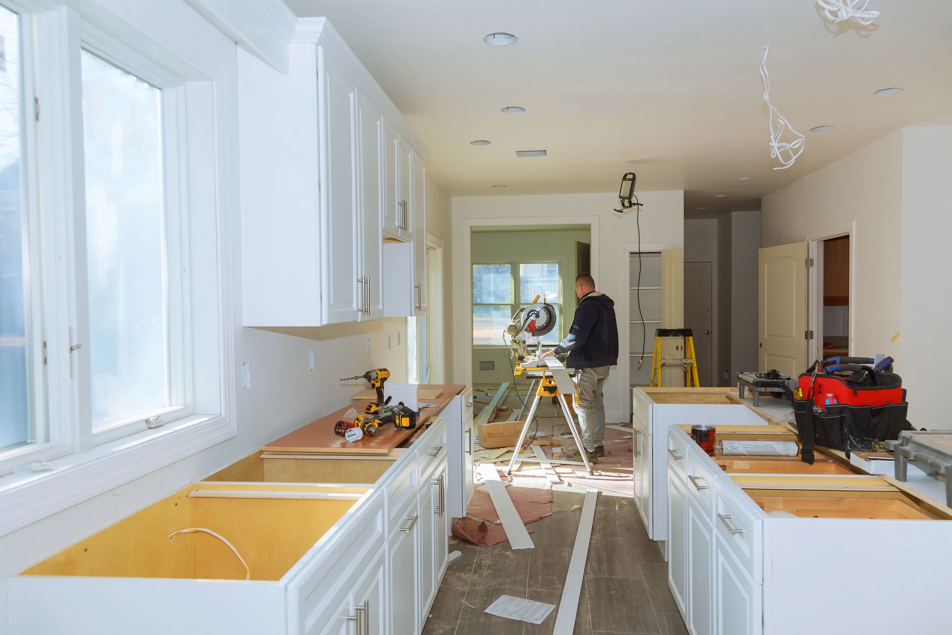 Kitchen renovation in progress, cabinets and a worker with a saw.
