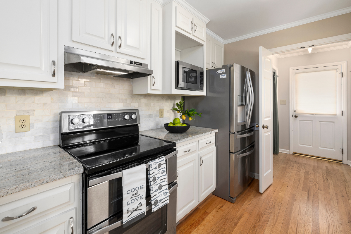 A kitchen with stainless steel appliances and white cabinets.