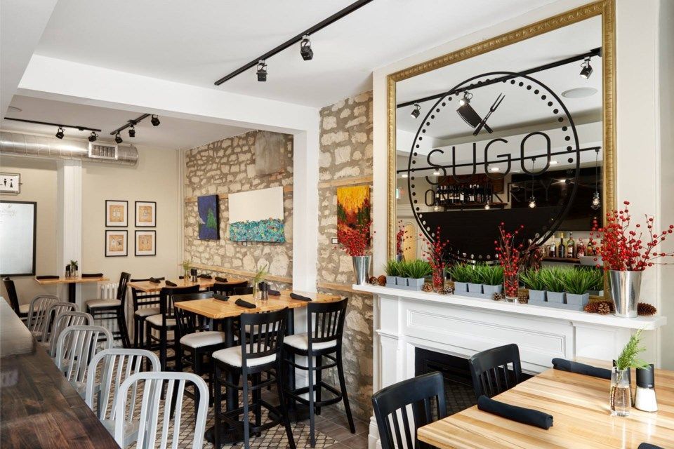 Restaurant interior with tables, chairs, stone wall, and a large mirror.