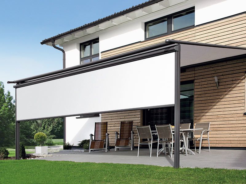 Ein Haus mit einer Terrasse mit Tisch und Stühlen unter einer weißen Markise.