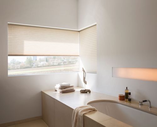 Ein Badezimmer mit Badewanne und einem Fenster mit Jalousien.