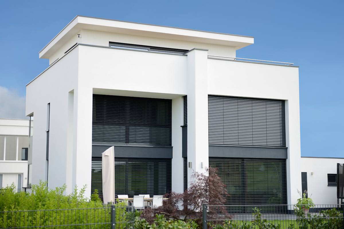 Ein weißes Haus mit schwarzen Jalousien an den Fenstern