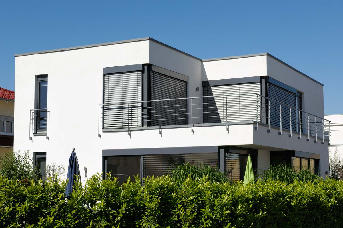 Ein weißes Haus mit einem Balkon und Sonnenschirmen davor