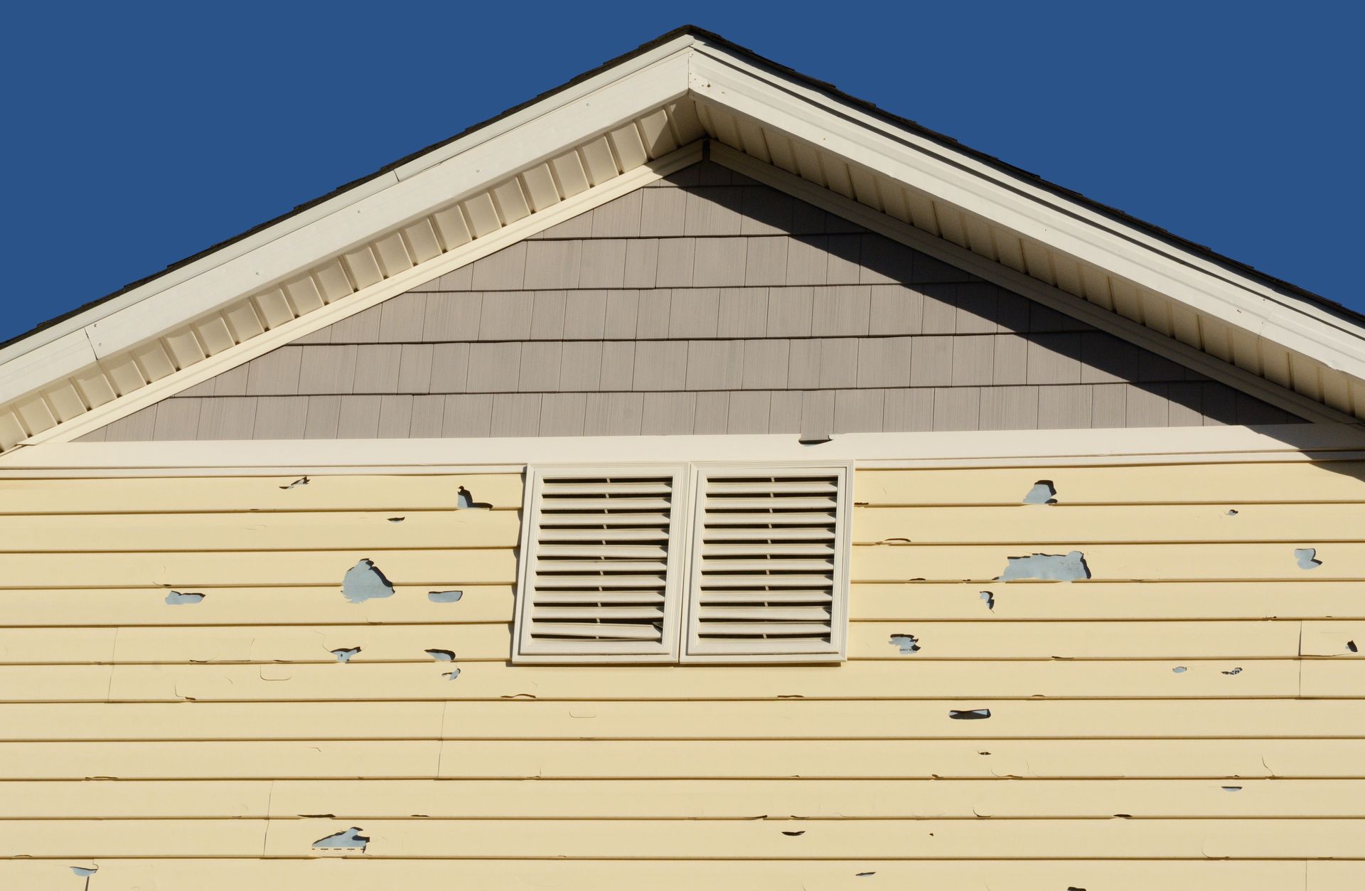 Holes in exterior siding in home from damage by hail storm.