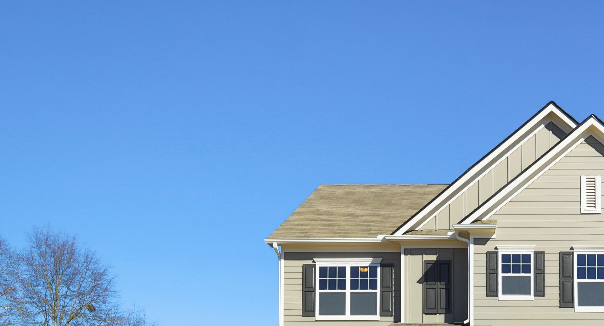 Home with beige exterior showcasing a shingled roof, representing residential siding contractor.