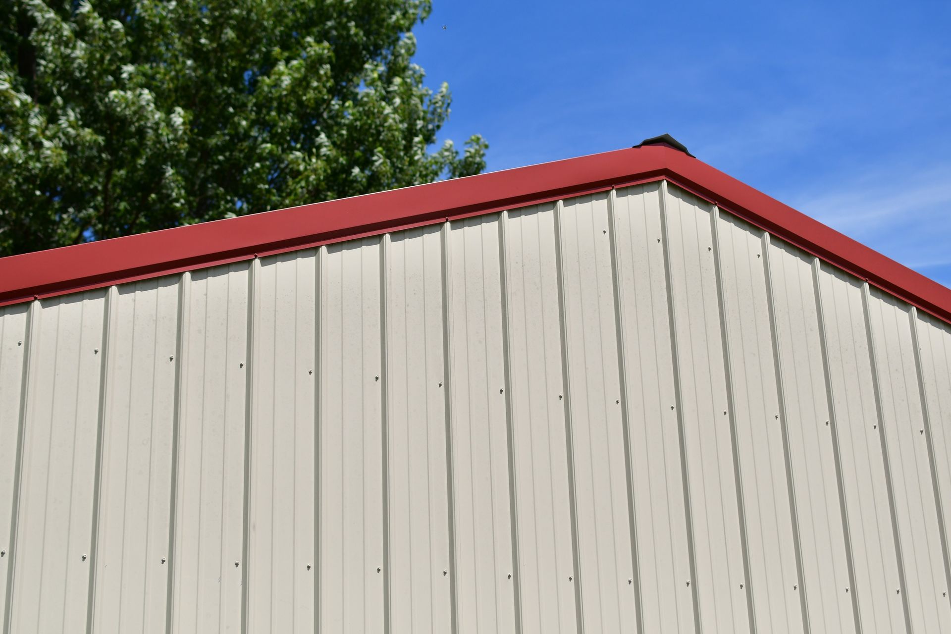 White vertical steel siding panels with red roofline trim.