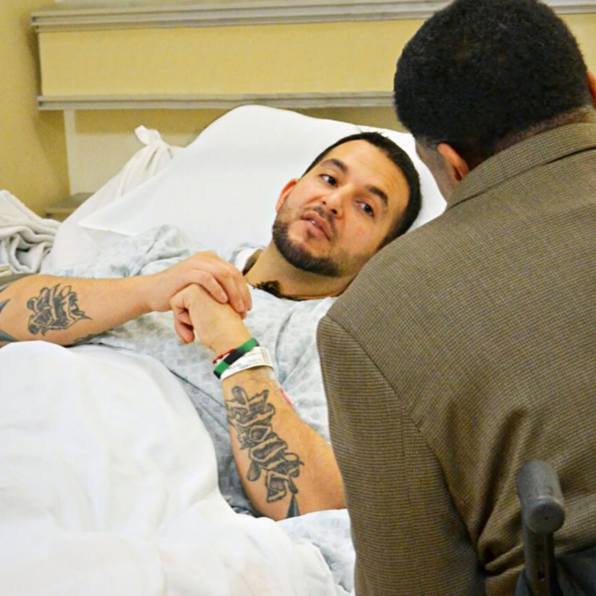 A man with a tattoo on his arm is laying in a hospital bed