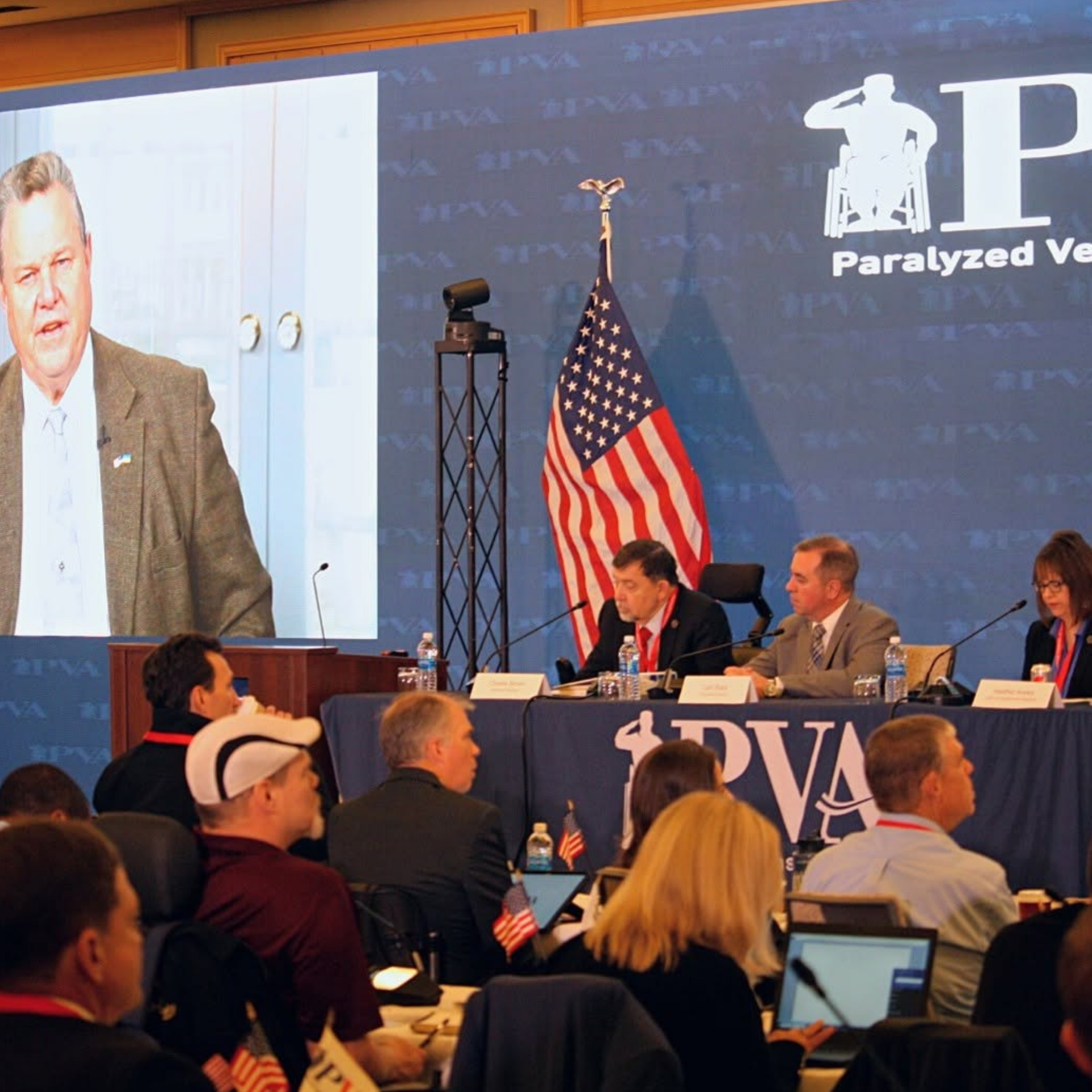 A group of people sitting in front of a paralyzed veteran sign