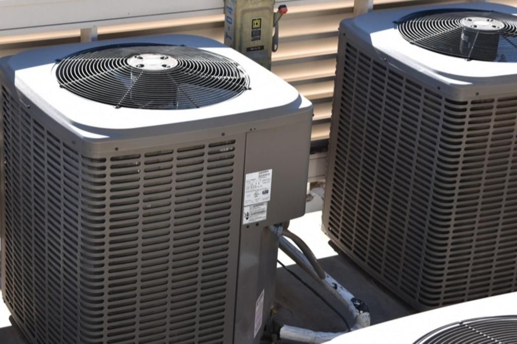 Two air conditioners are sitting next to each other on a roof