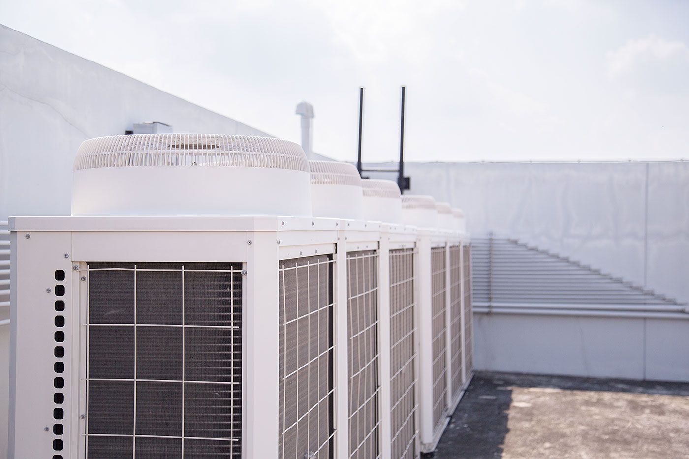 A row of air conditioners on the roof of a building.