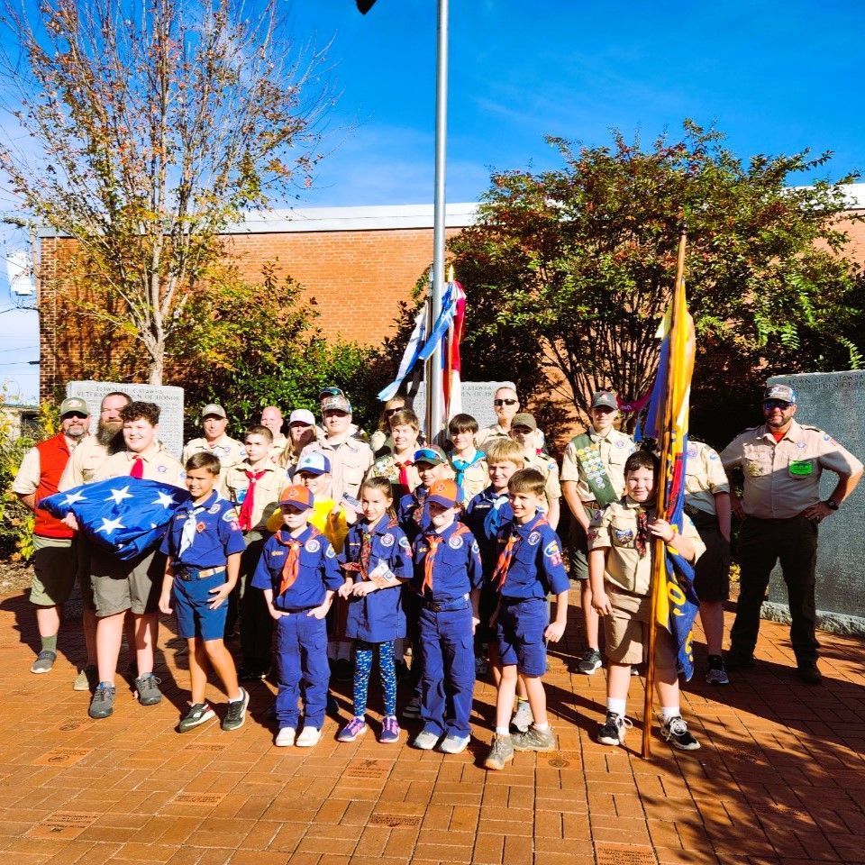A group of boy scouts standing in front of a flag pole
