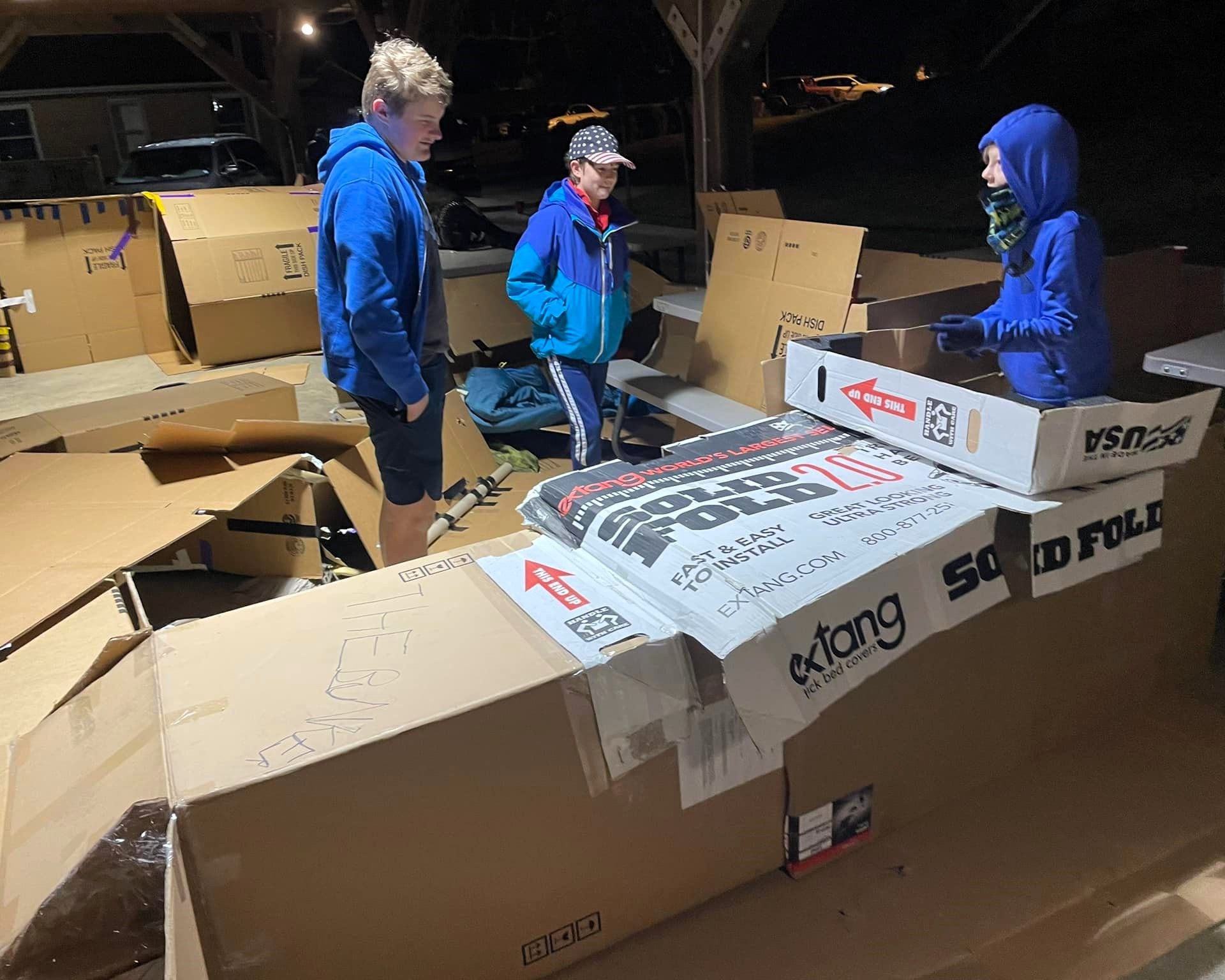 A group of people are standing around a pile of cardboard boxes.