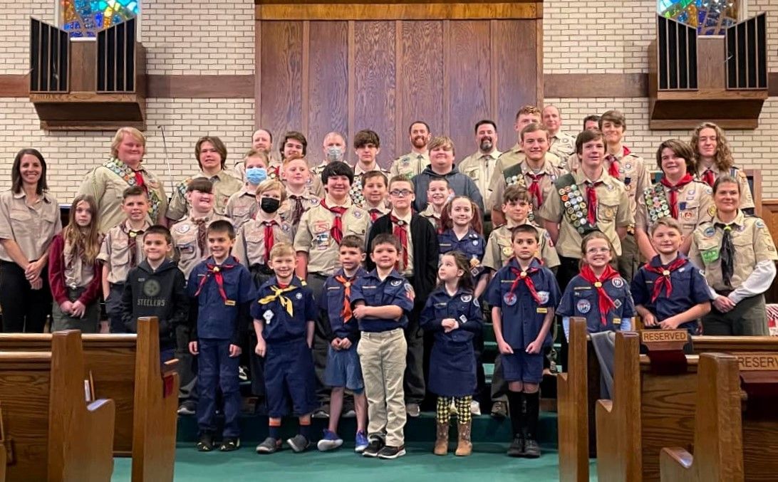 A group of boy scouts are posing for a picture in a church.