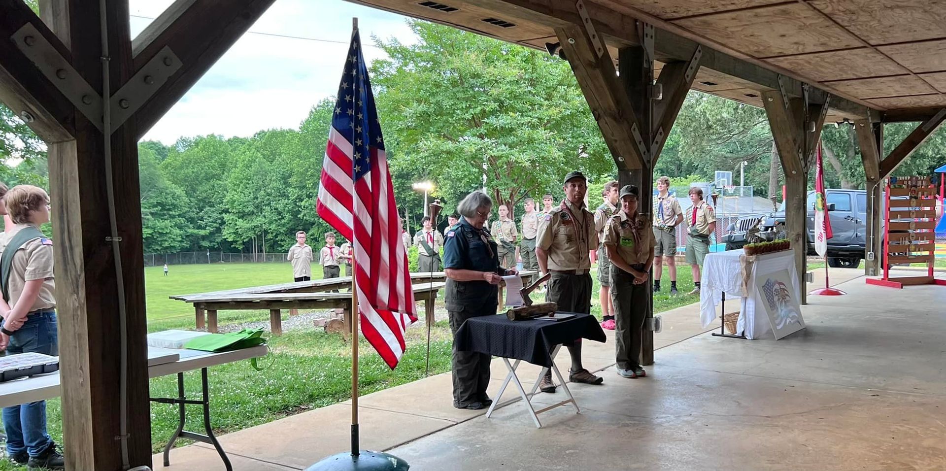 A group of people standing under a covered area with an american flag.